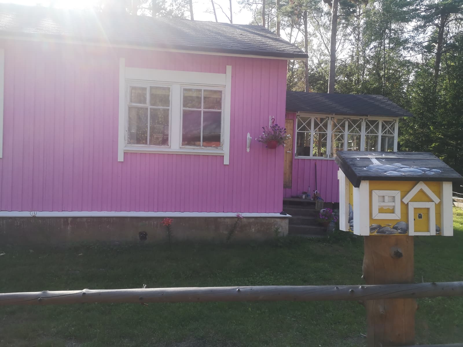 A pink wooden cottage with a yellow post box on Naissaar